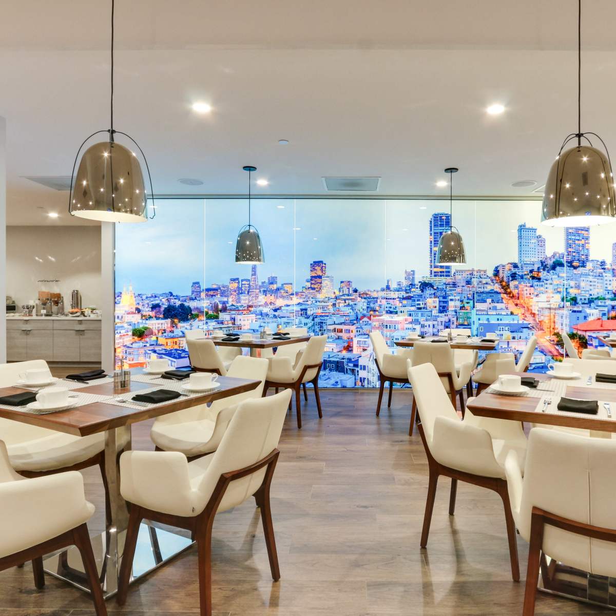 A modern dining area with white chairs and wooden tables, featuring a large mural of a city skyline on the wall.
