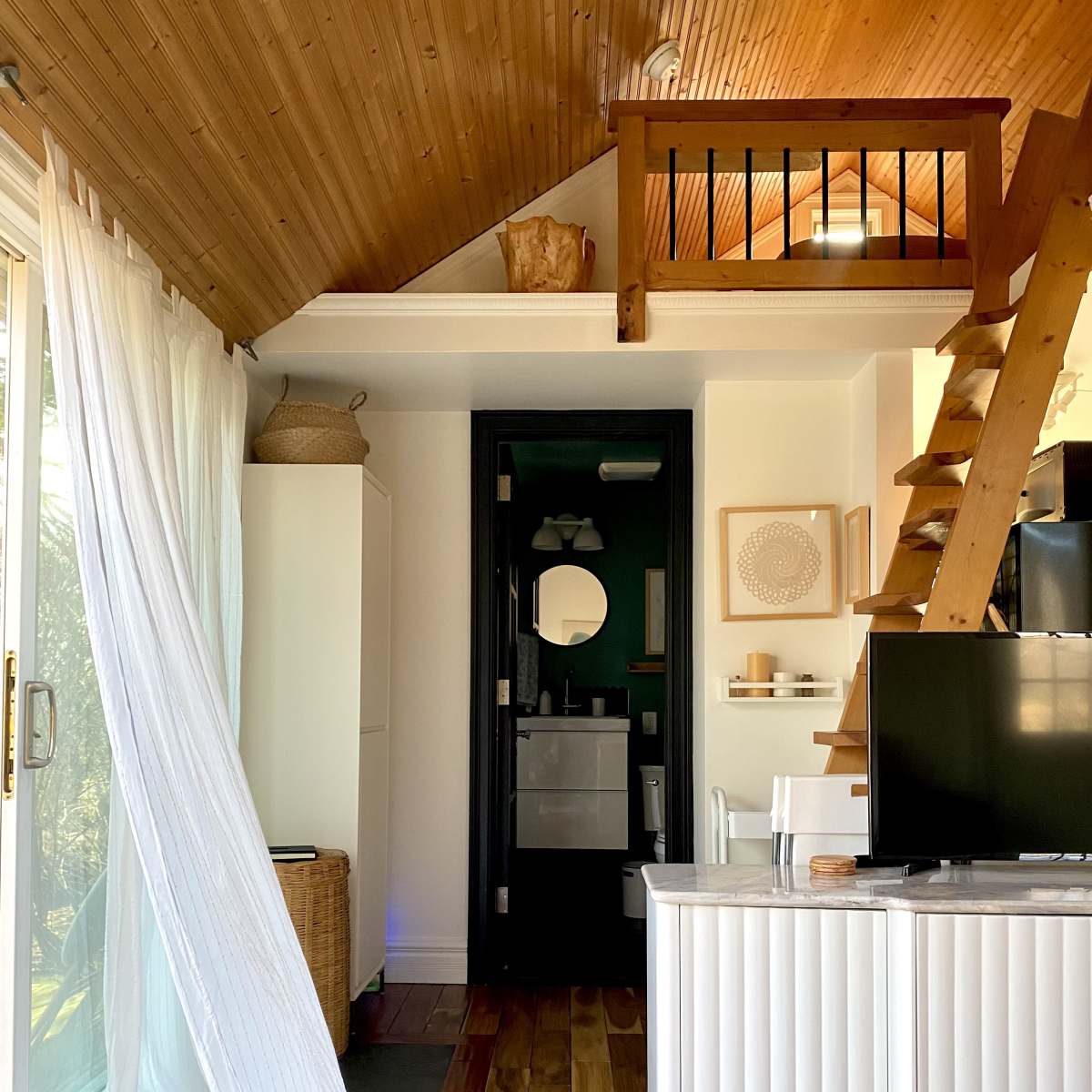 A cozy interior space featuring a staircase, a television, and a doorway leading to a bathroom.