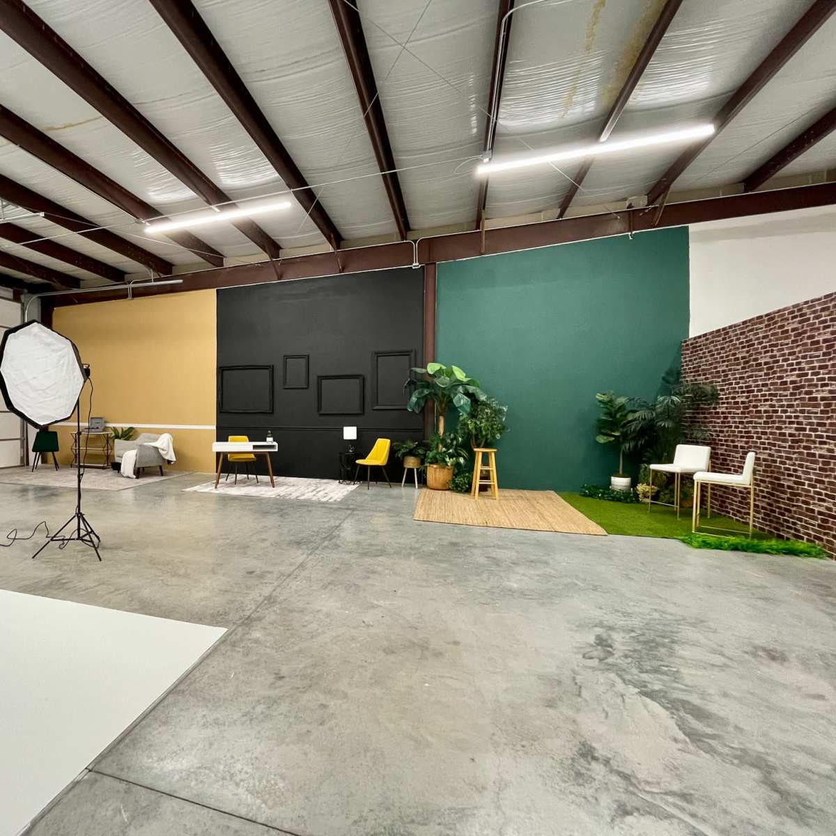 A spacious studio with a variety of seating arrangements, a large backdrop, and distinct color-blocked walls.