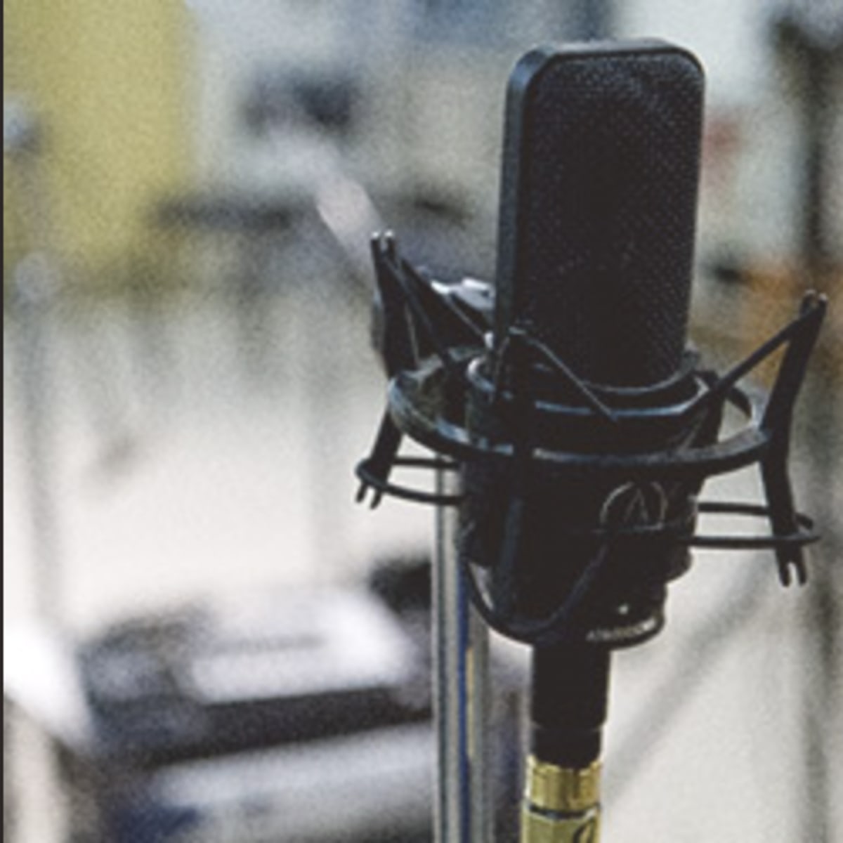 A studio microphone on a stand next to a pop filter in a recording environment.