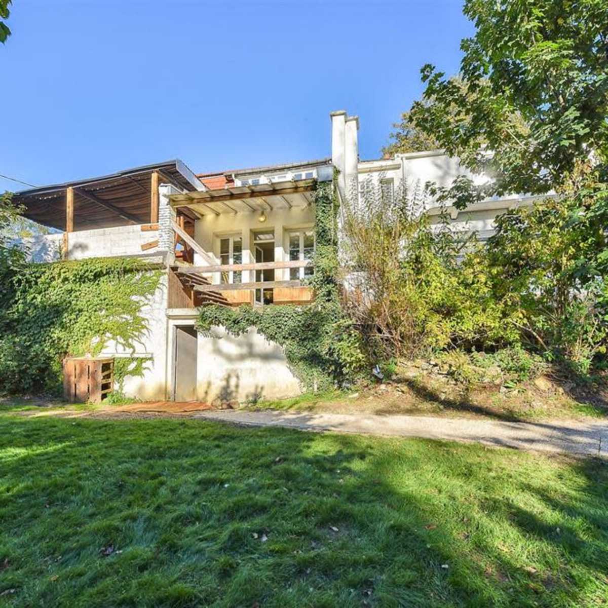 A modern two-story house surrounded by greenery and a well-maintained lawn.