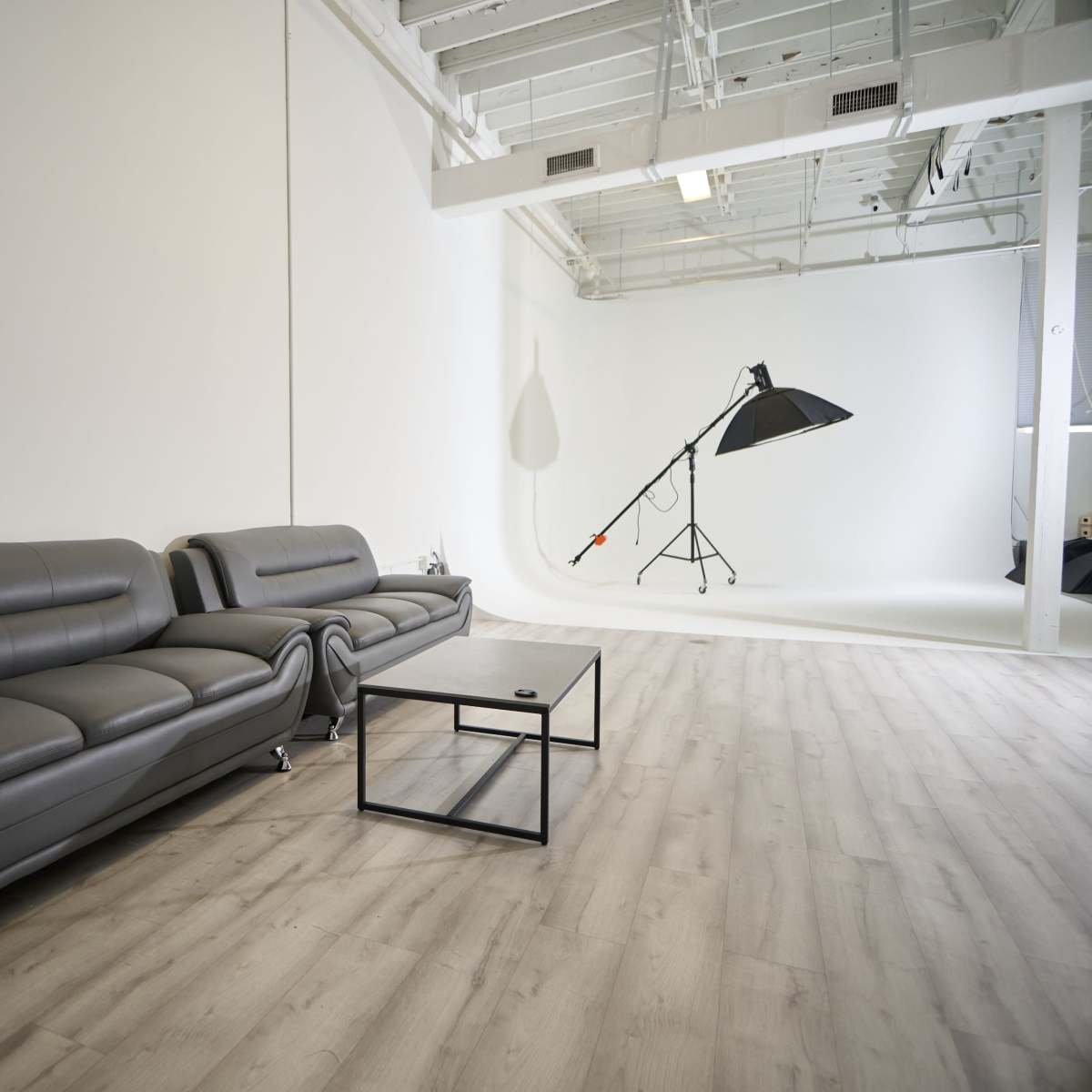 A modern interior space featuring two gray sofas and a black coffee table, with a large lighting setup in the background.