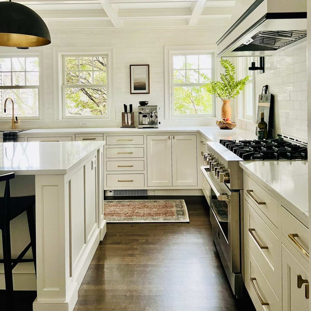The kitchen features white cabinetry, a gray countertop, stainless steel appliances, and natural light streaming through multiple windows.