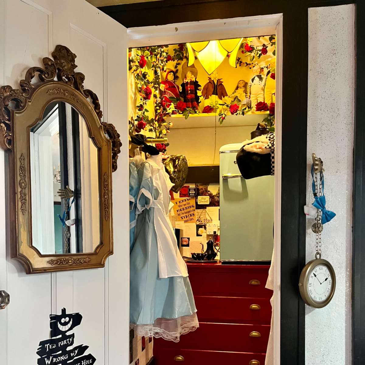 An open closet with a mirror, colorful decorations, a blue dress, and a checkered floor pattern.