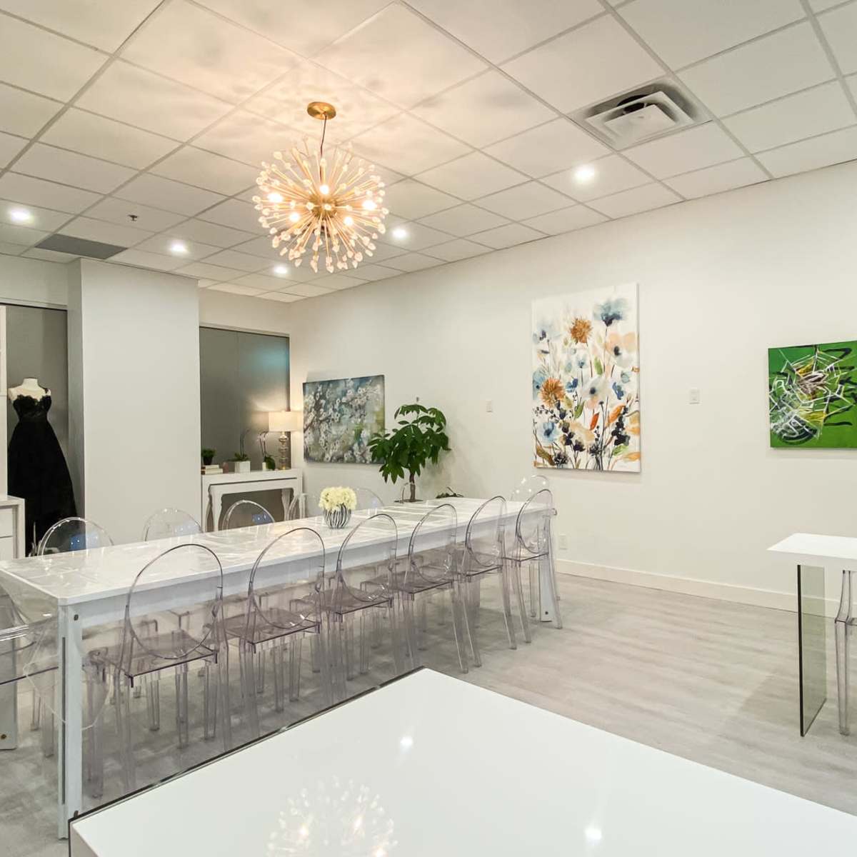 A modern meeting room with a long transparent table, acrylic chairs, and colorful artwork on the walls.