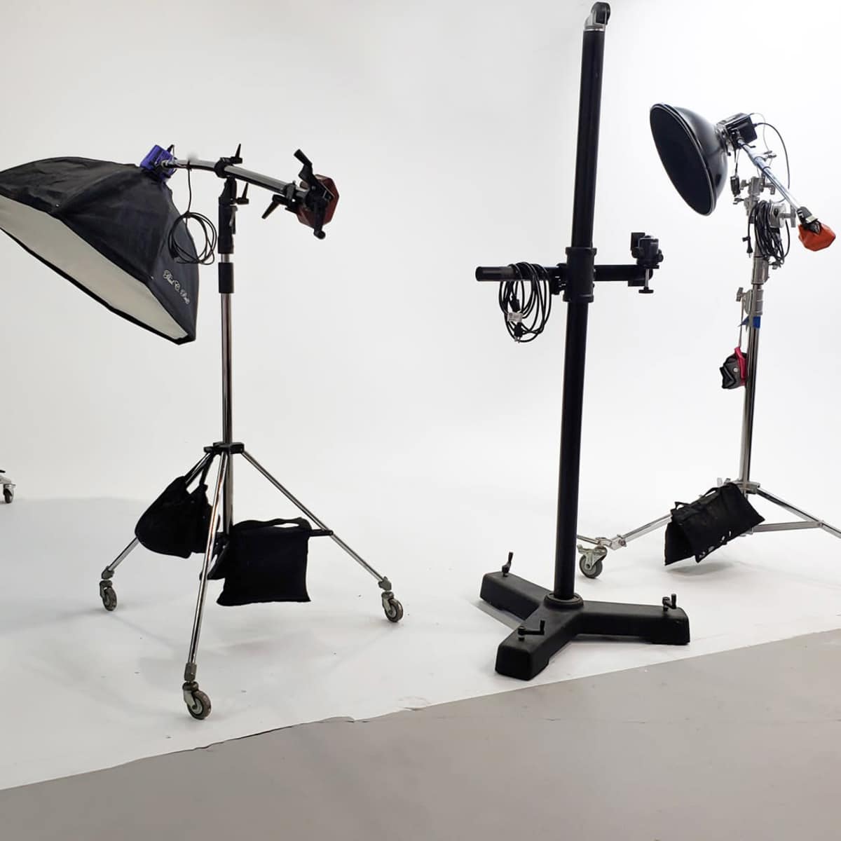 A photography studio setup with three light stands, a softbox, and a backdrop.