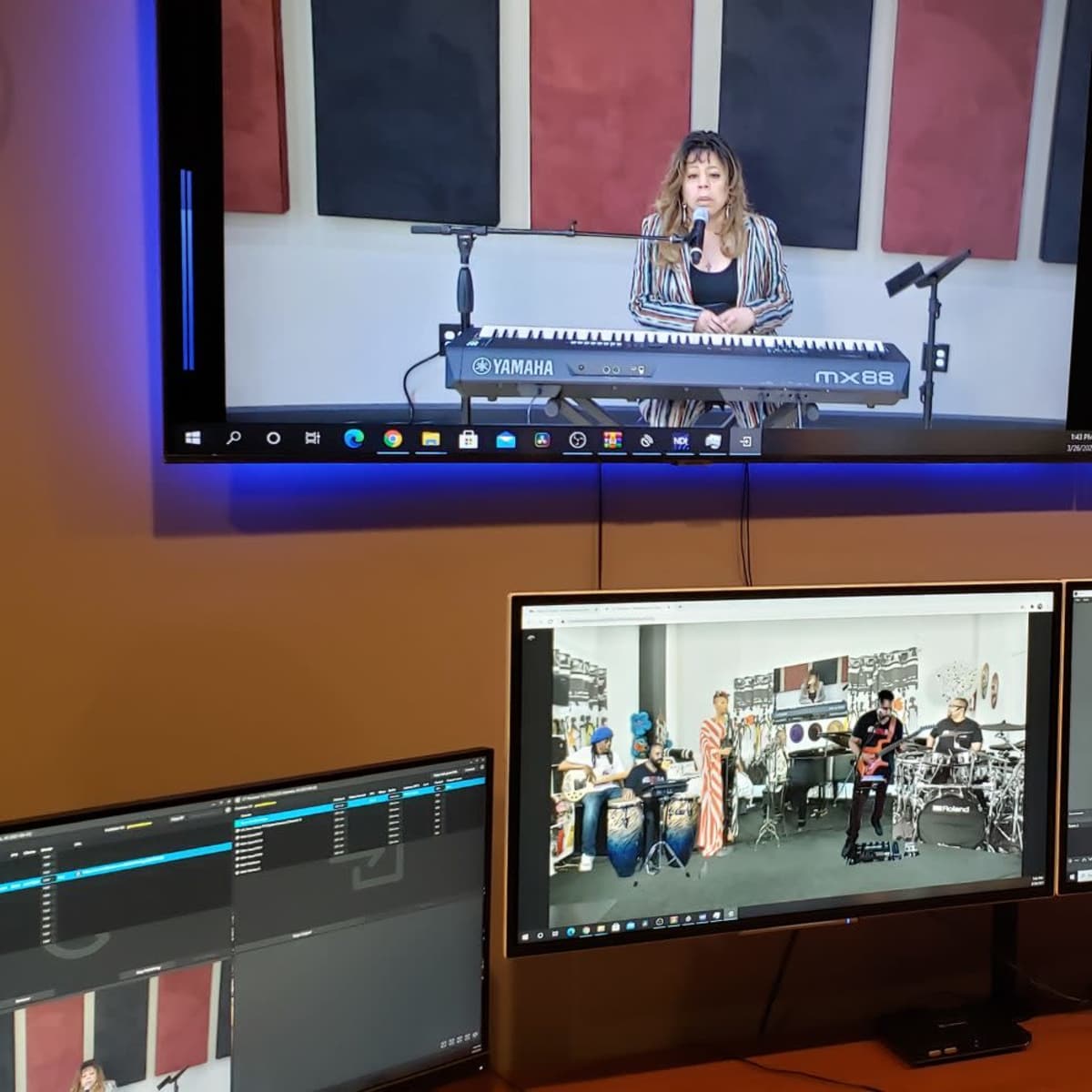 A person is performing on a keyboard in a recording studio, with multiple screens displaying the performance and video editing software.