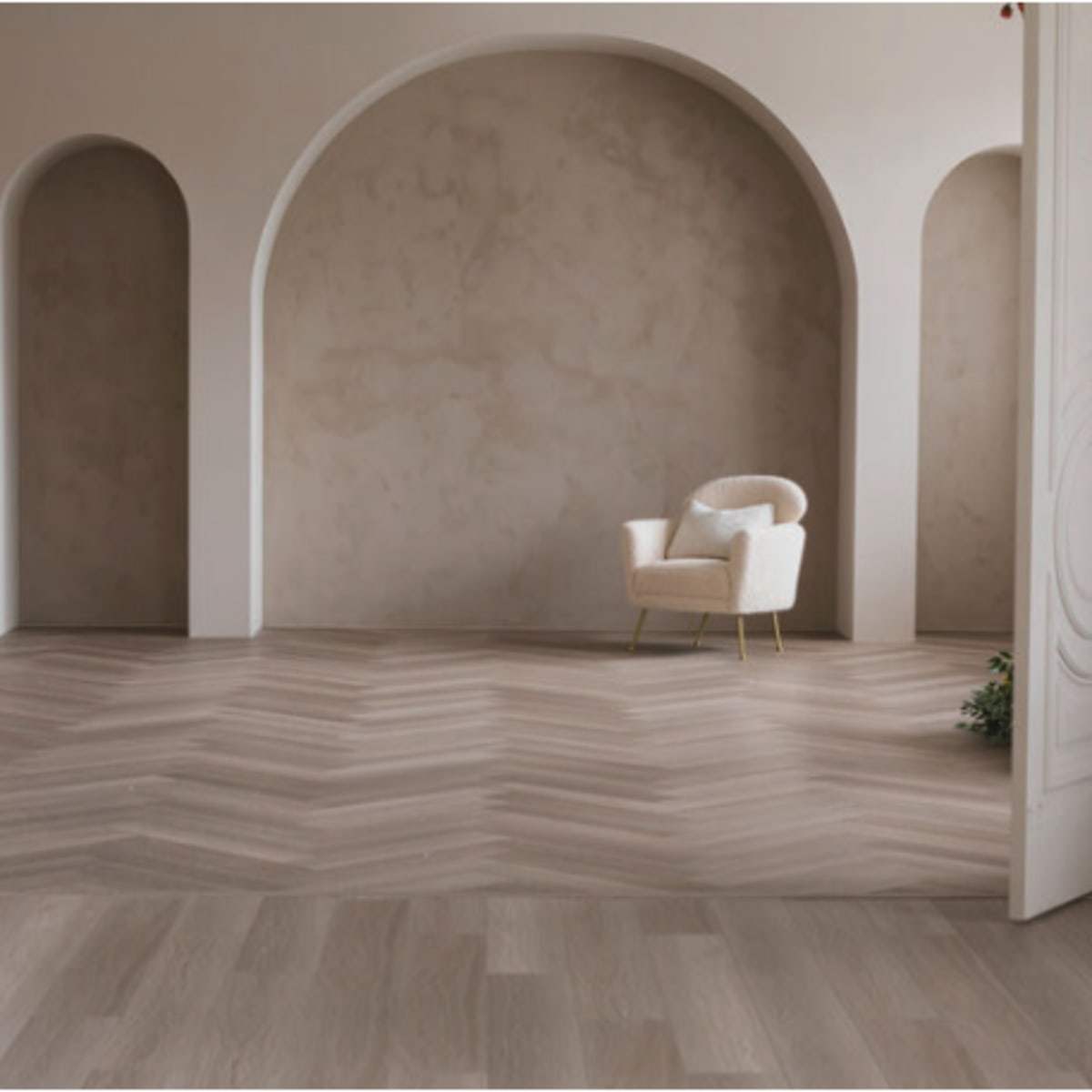 A minimalistic interior space features a chair in front of an arched wall, with herringbone-patterned flooring and double doors framing the scene.