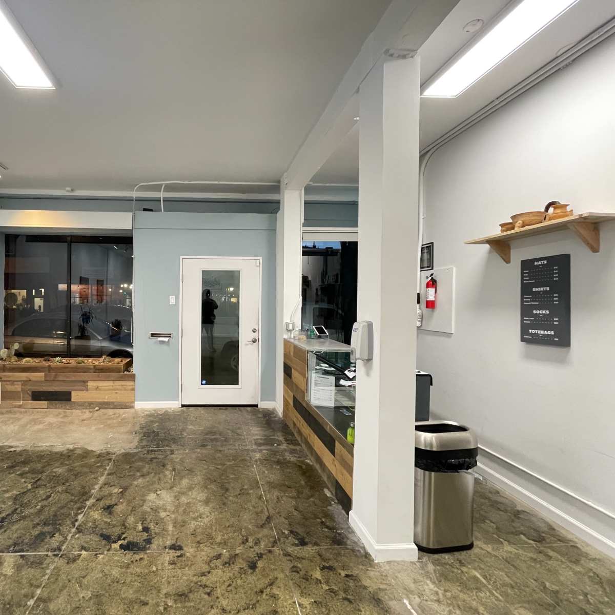 A spacious, minimalistic interior of a commercial space with a reception area, a large window, and a door leading outside.