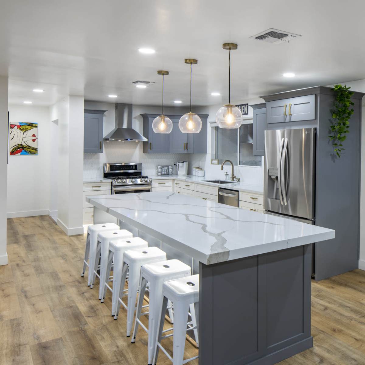 The modern kitchen features a large island with bar stools, stainless steel appliances, and a spacious layout with ample natural light.