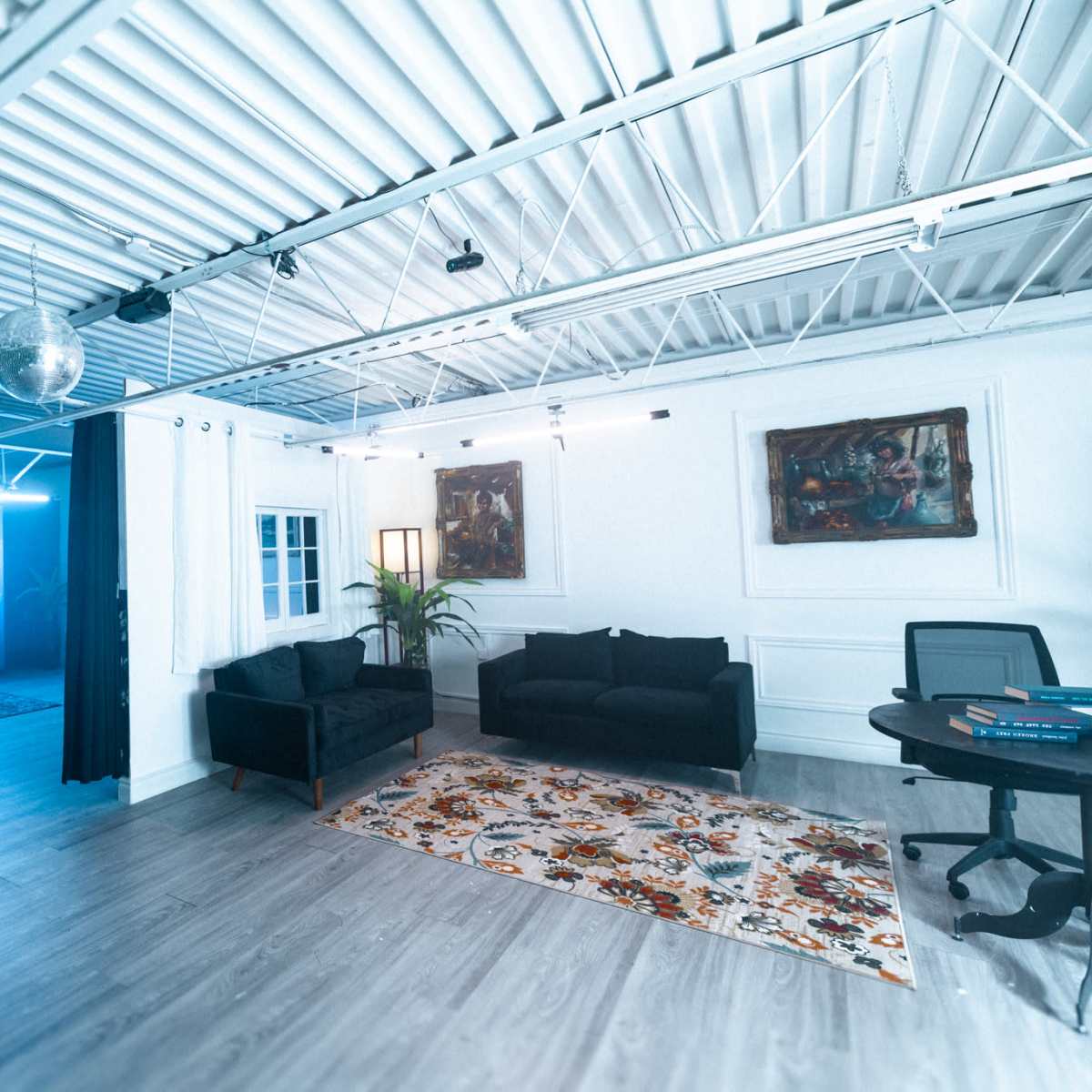 A modern office space features a seating area with dark couches, a large decorative rug, and a backdrop of a celestial-themed mural.