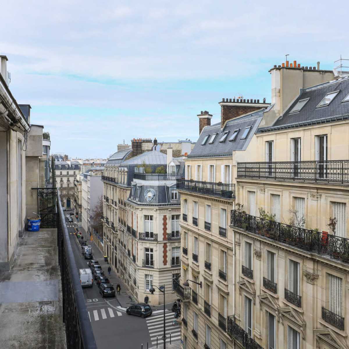 A city street in Paris lined with classic, five-story buildings and a clear sky overhead.