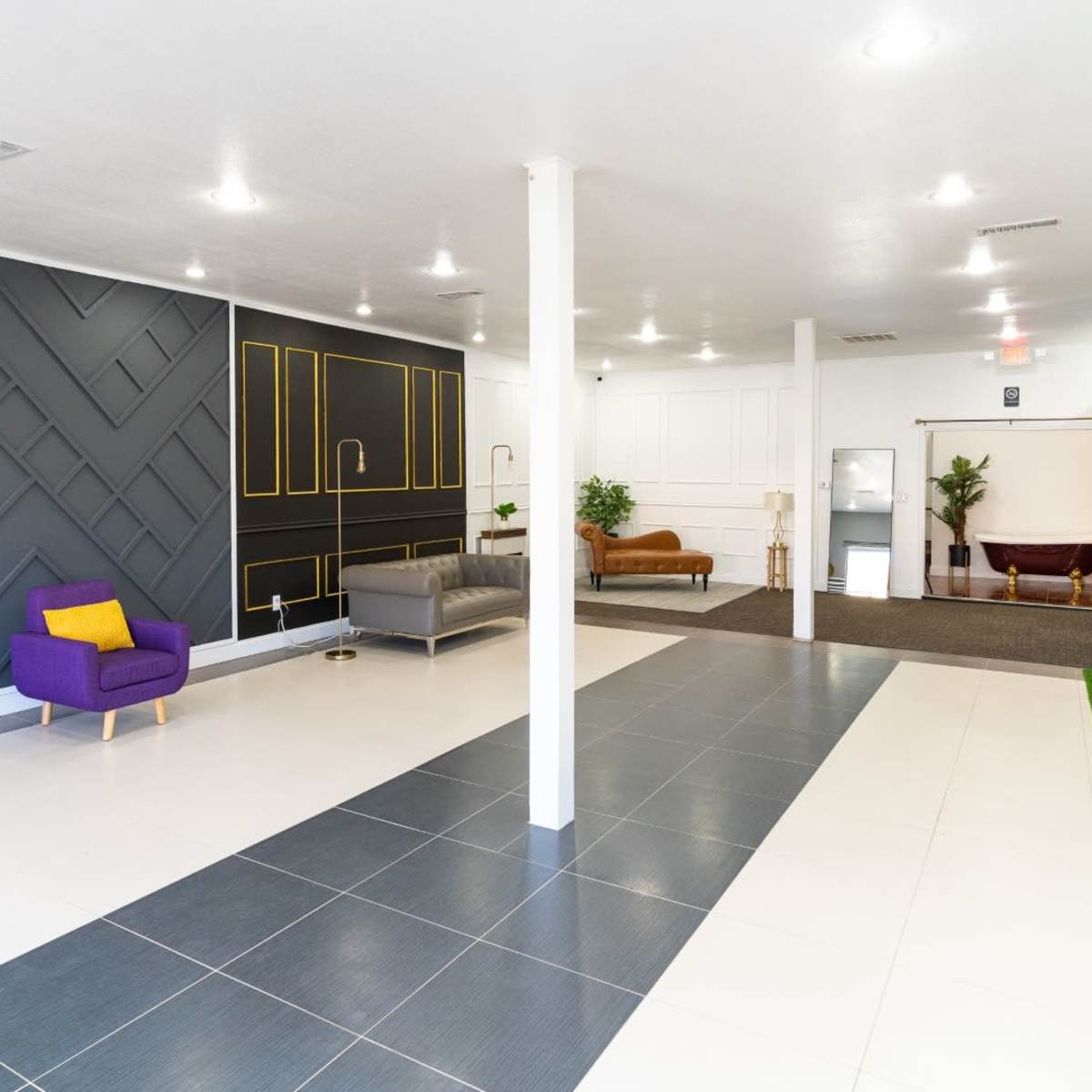 A spacious, modern interior featuring a mix of dark and light wall designs, stylish seating areas, and green accents.