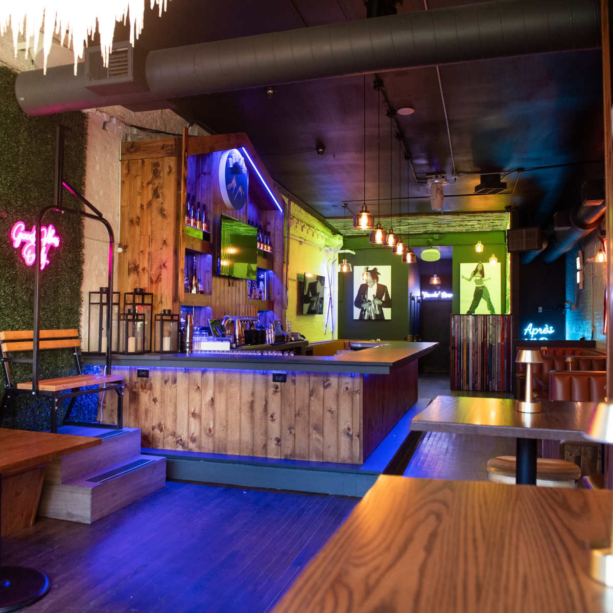 A modern bar interior featuring wooden accents, neon lights, and a well-lit counter with seating options.