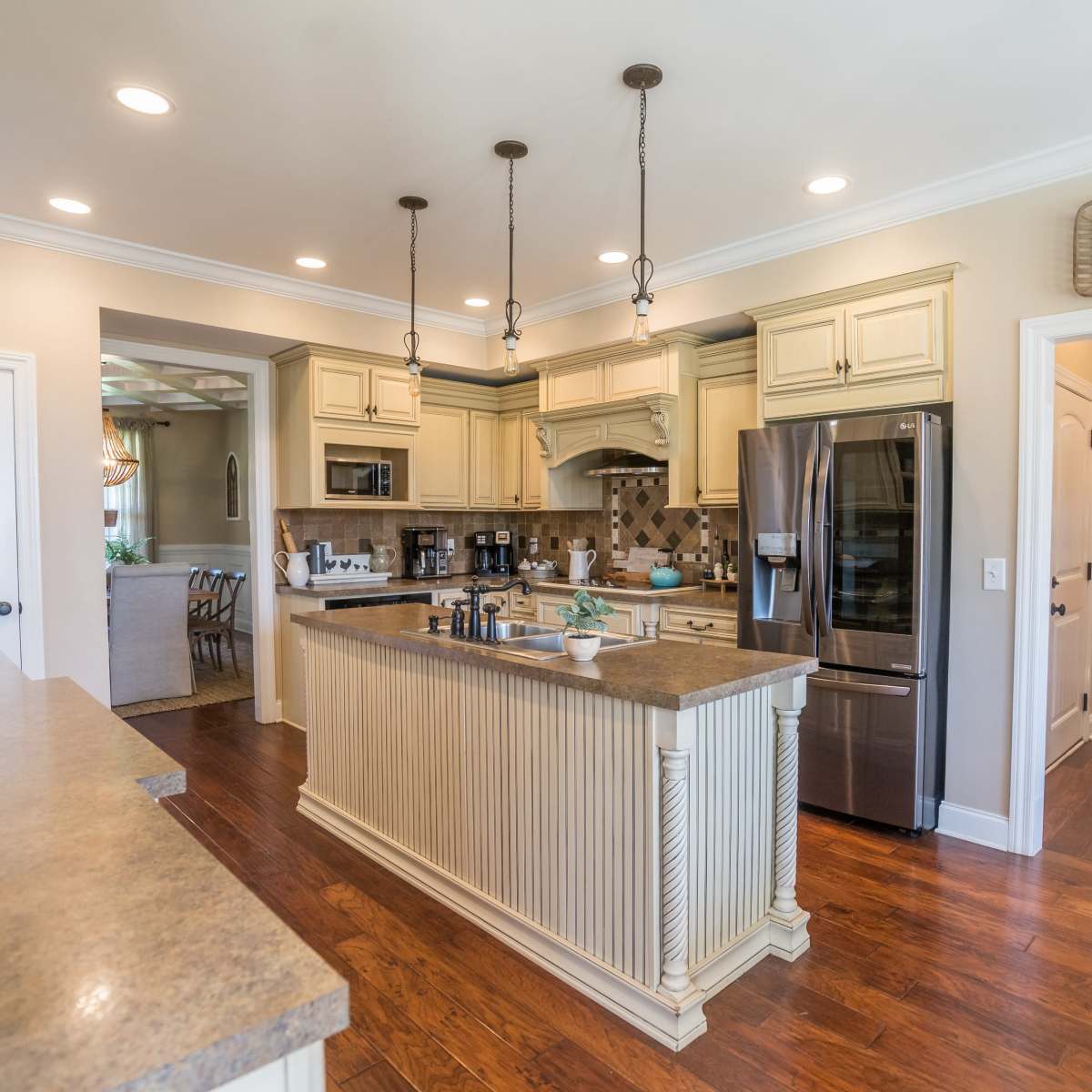 A spacious kitchen with a central island, stainless steel appliances, and pendant lighting above the countertop.