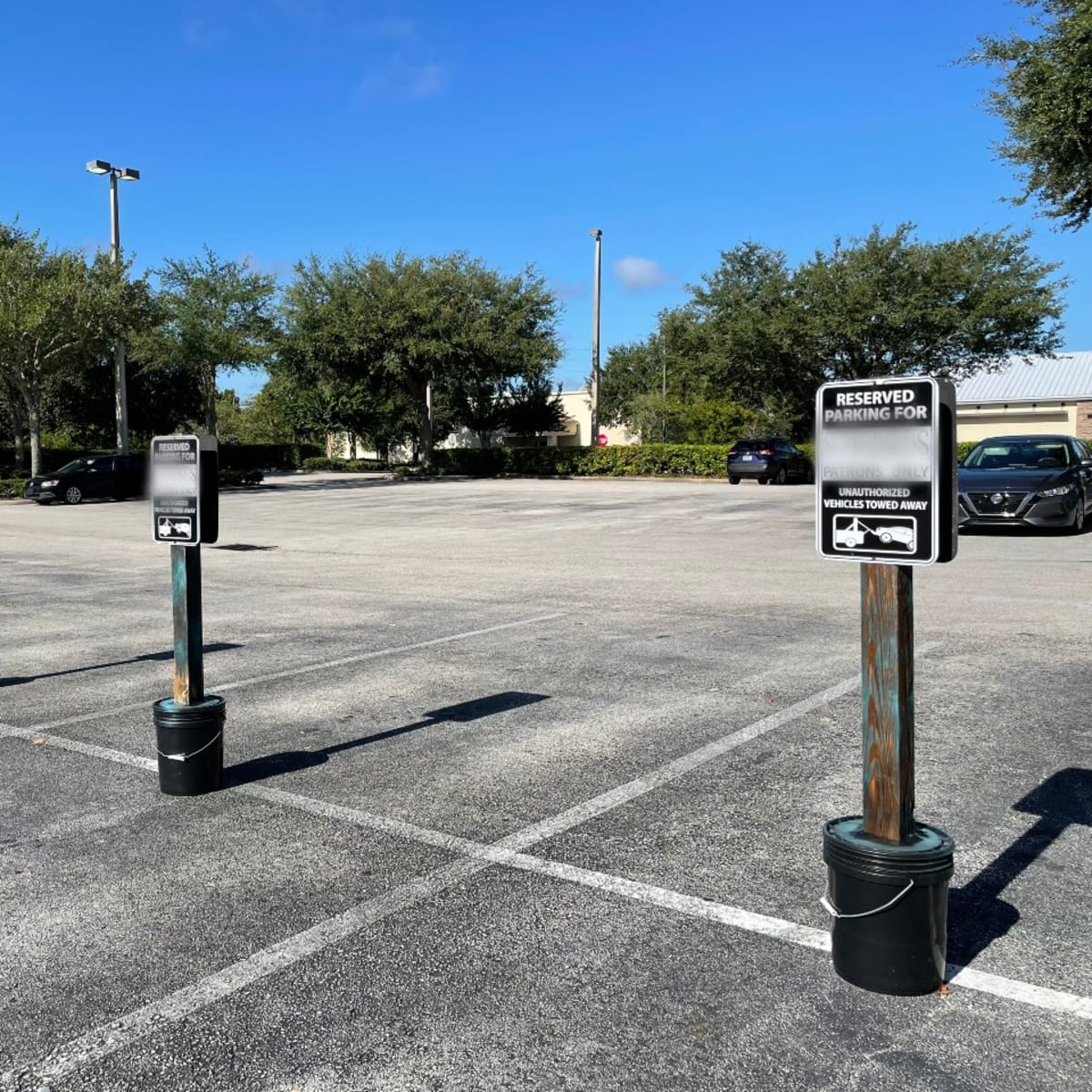 Four parking poles in a nearly empty parking lot, each with a sign indicating reserved parking.