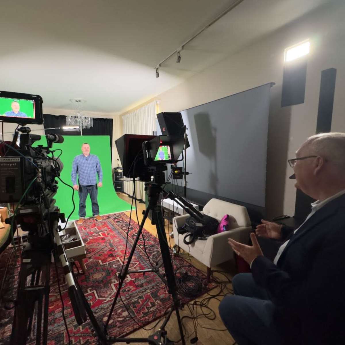 A man stands in front of a green screen while being filmed by multiple cameras in a well-lit studio setting.