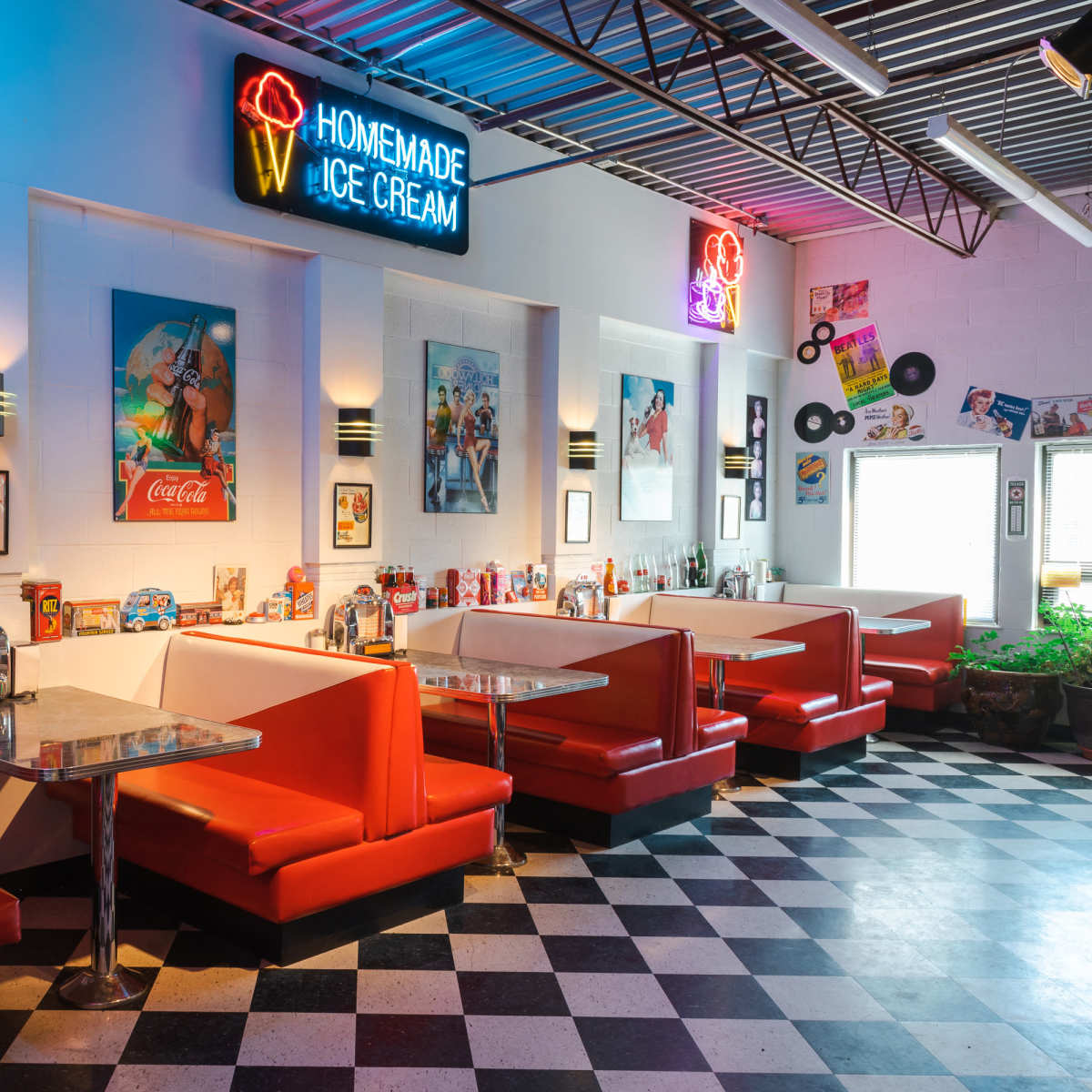 A retro diner with red booths, a checkered floor, and neon signs advertising homemade ice cream.