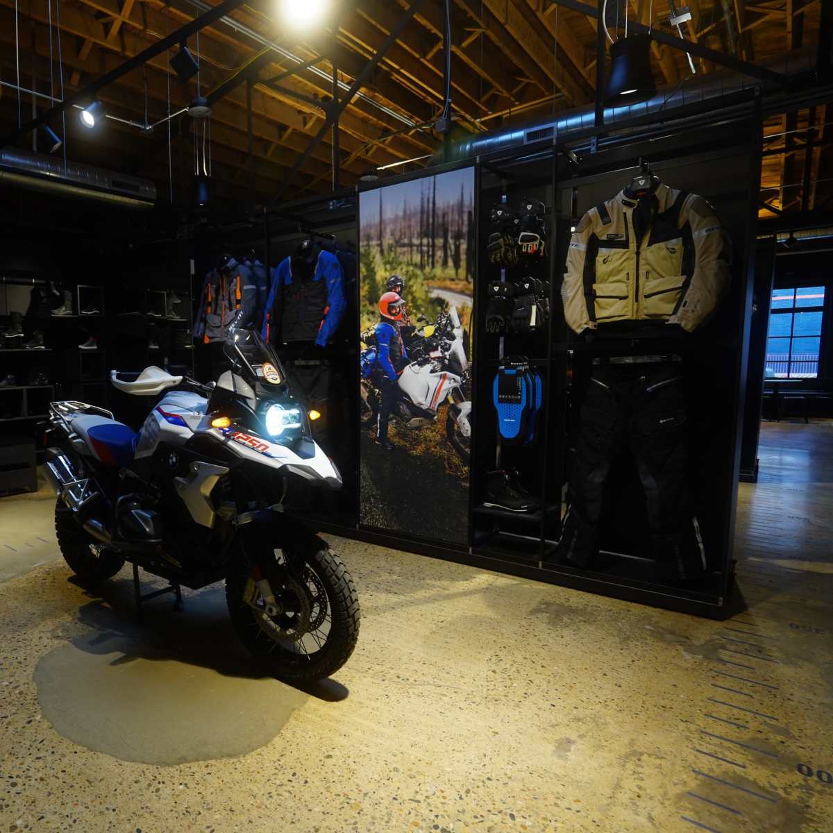 A motorcycle is displayed at the center of a retail space surrounded by motorcycle gear and apparel.