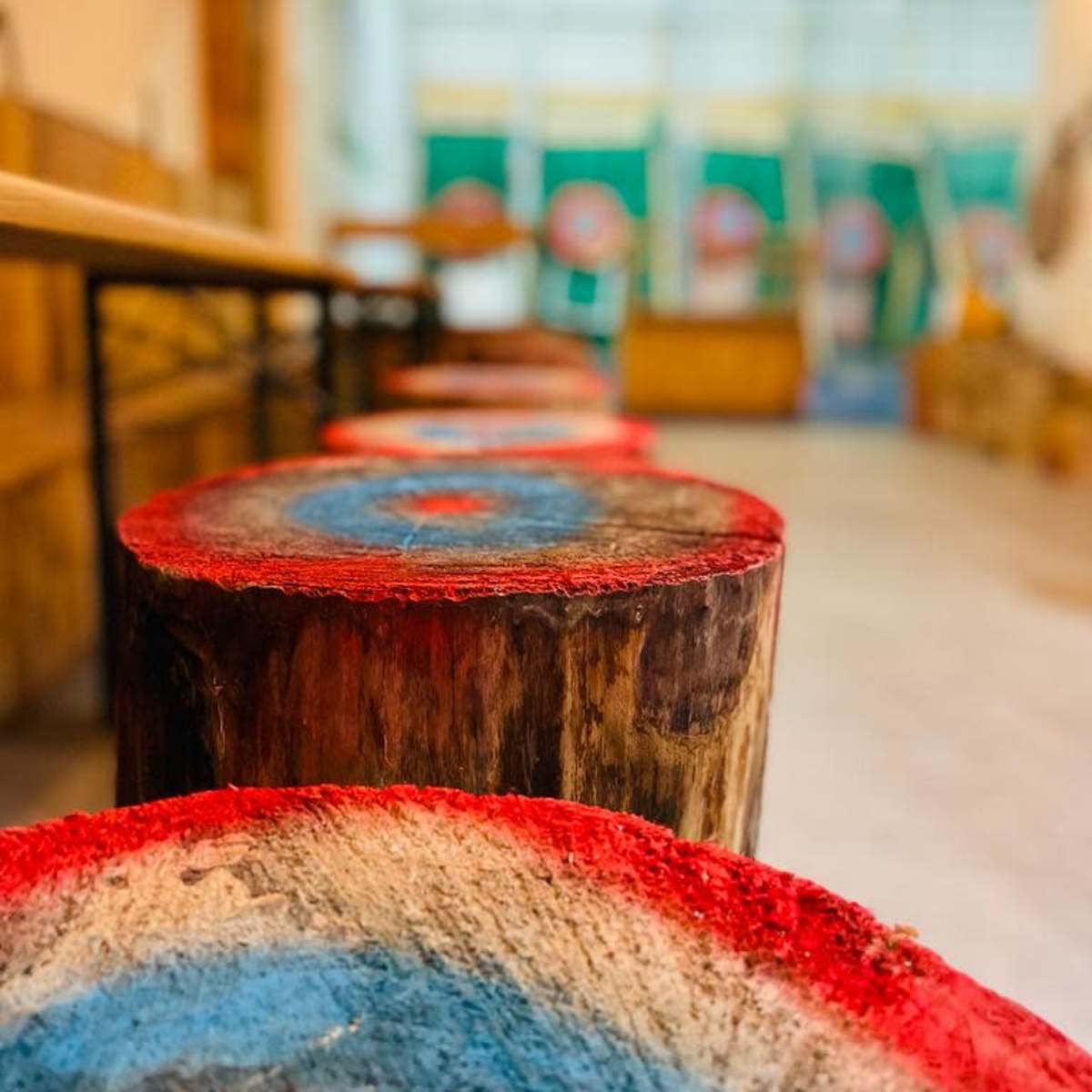 A line of wooden targets with painted blue and red bullseyes, positioned in an indoor axe-throwing venue.