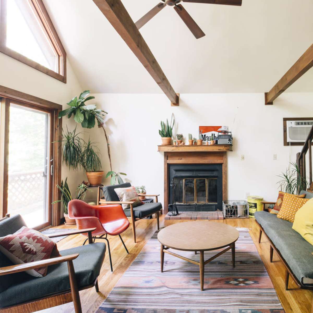 A modern living room featuring two sofas, a coffee table, a fireplace, and large windows with natural light.