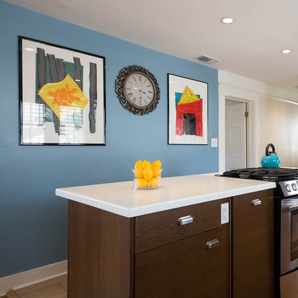 A modern kitchen features a gas stove, stainless steel appliances, and a prominent island with a bowl of lemons.