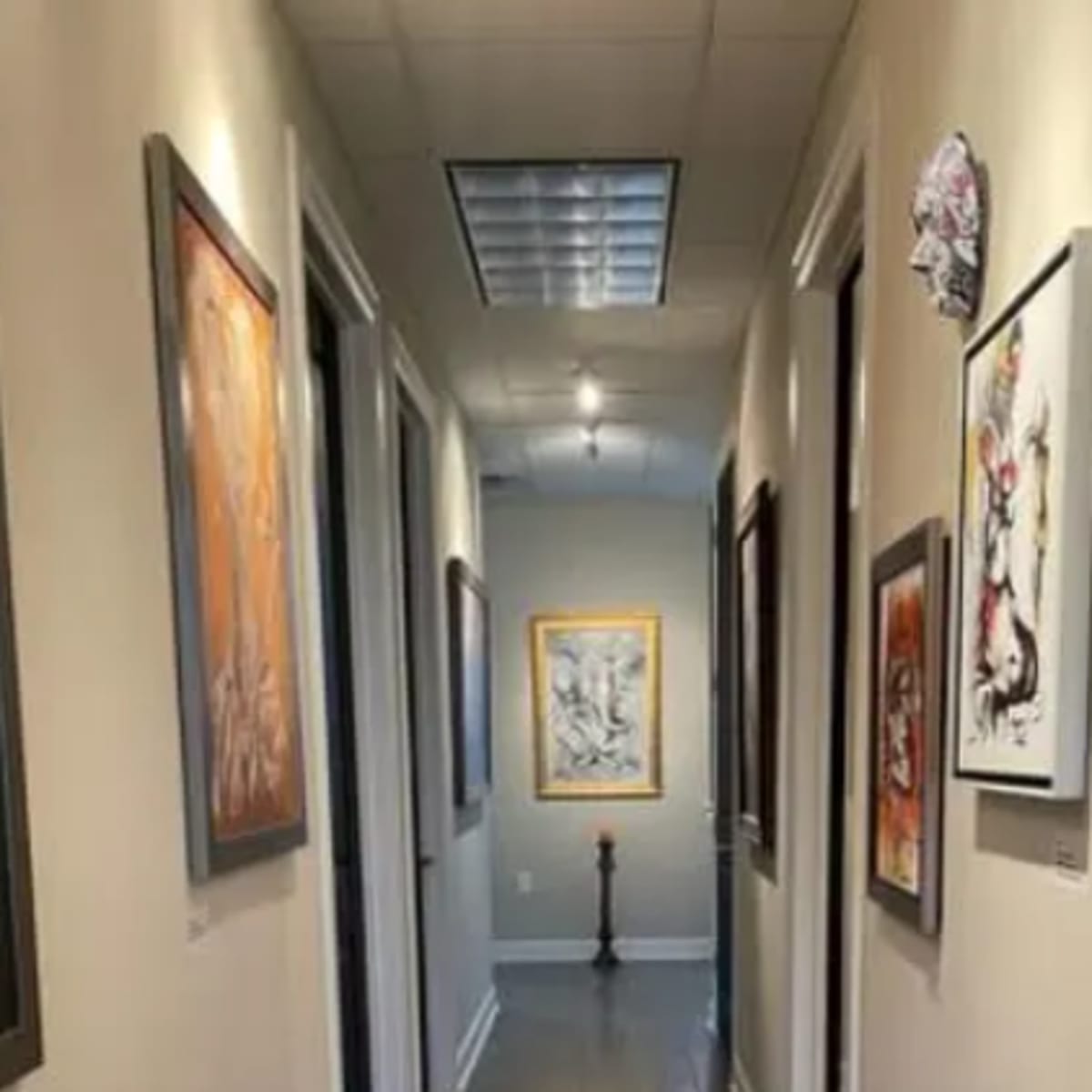 A corridor features several framed artworks on the walls alongside closed doors.