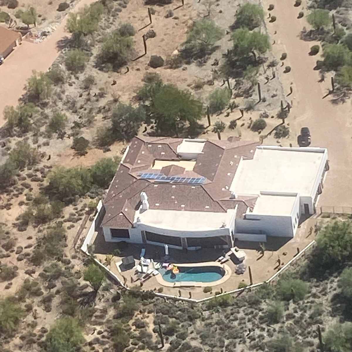 A modern house with a pool surrounded by desert vegetation.