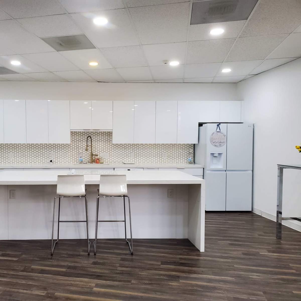 A modern kitchen features white cabinetry, a patterned backsplash, and a central island with two stools.