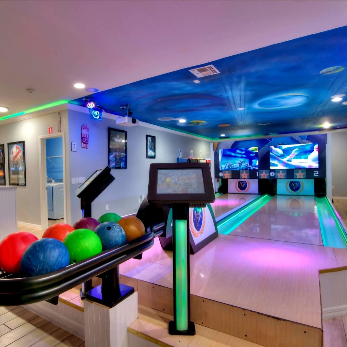 A modern bowling alley with a ball rack displaying colorful bowling balls and illuminated lanes.