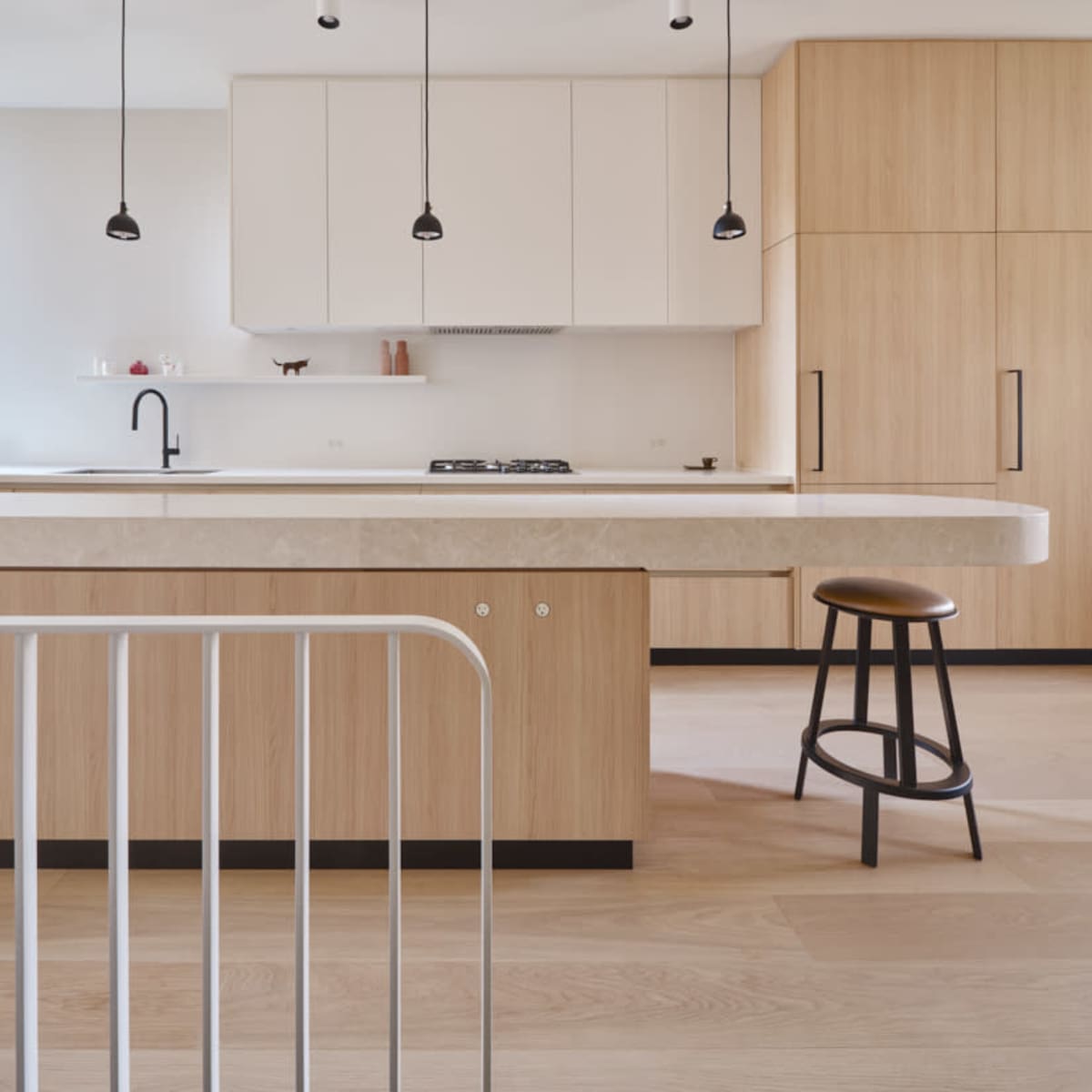 A modern kitchen featuring wooden cabinetry, a central island with a stone countertop, and pendant lights hanging from the ceiling.