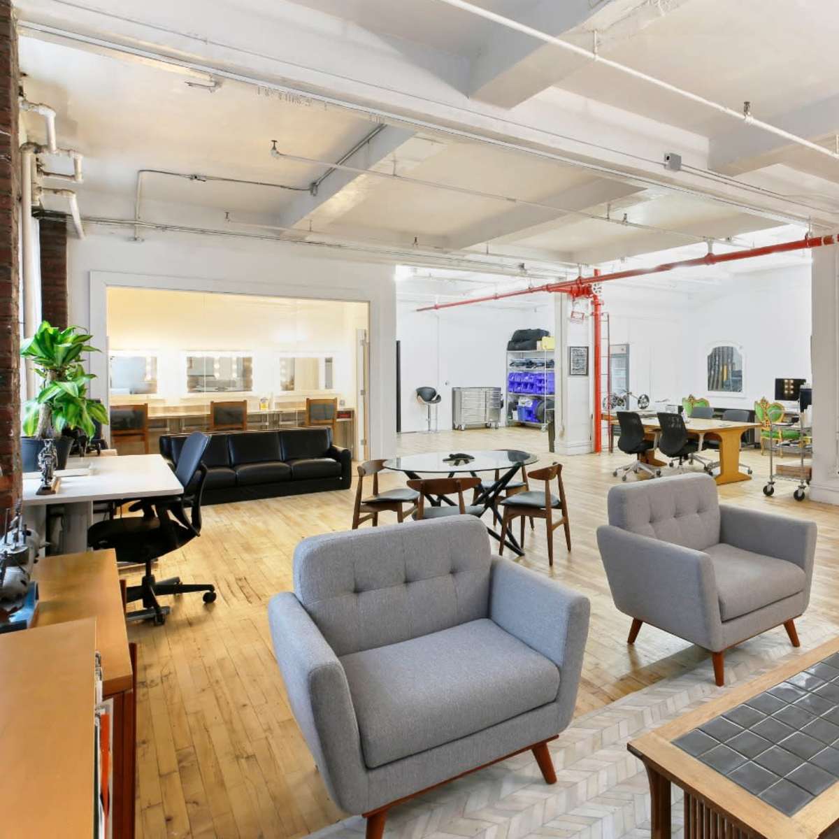 An open-plan office space with wooden floors, modern furniture, and areas for seating and workstations.