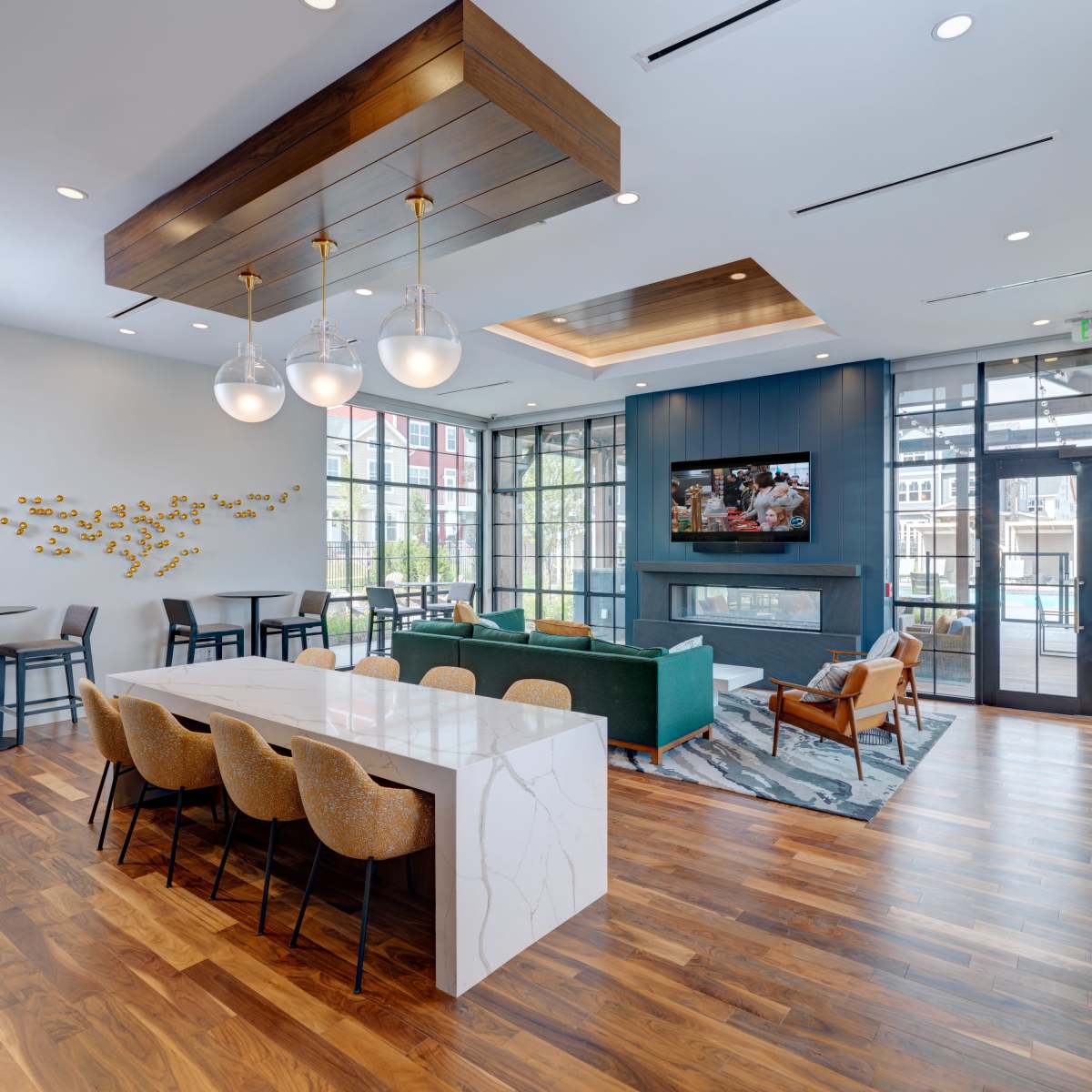 A modern common area with a seating arrangement, a large table, and windows that provide natural light.