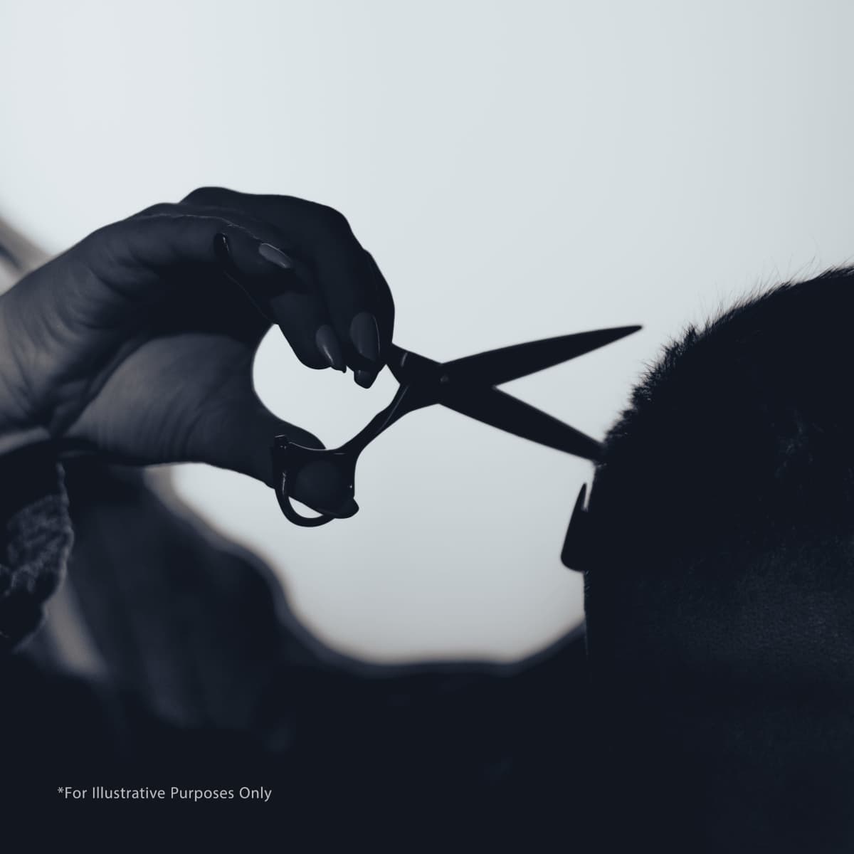 A hand holding scissors is poised above a person's head, ready to cut hair.