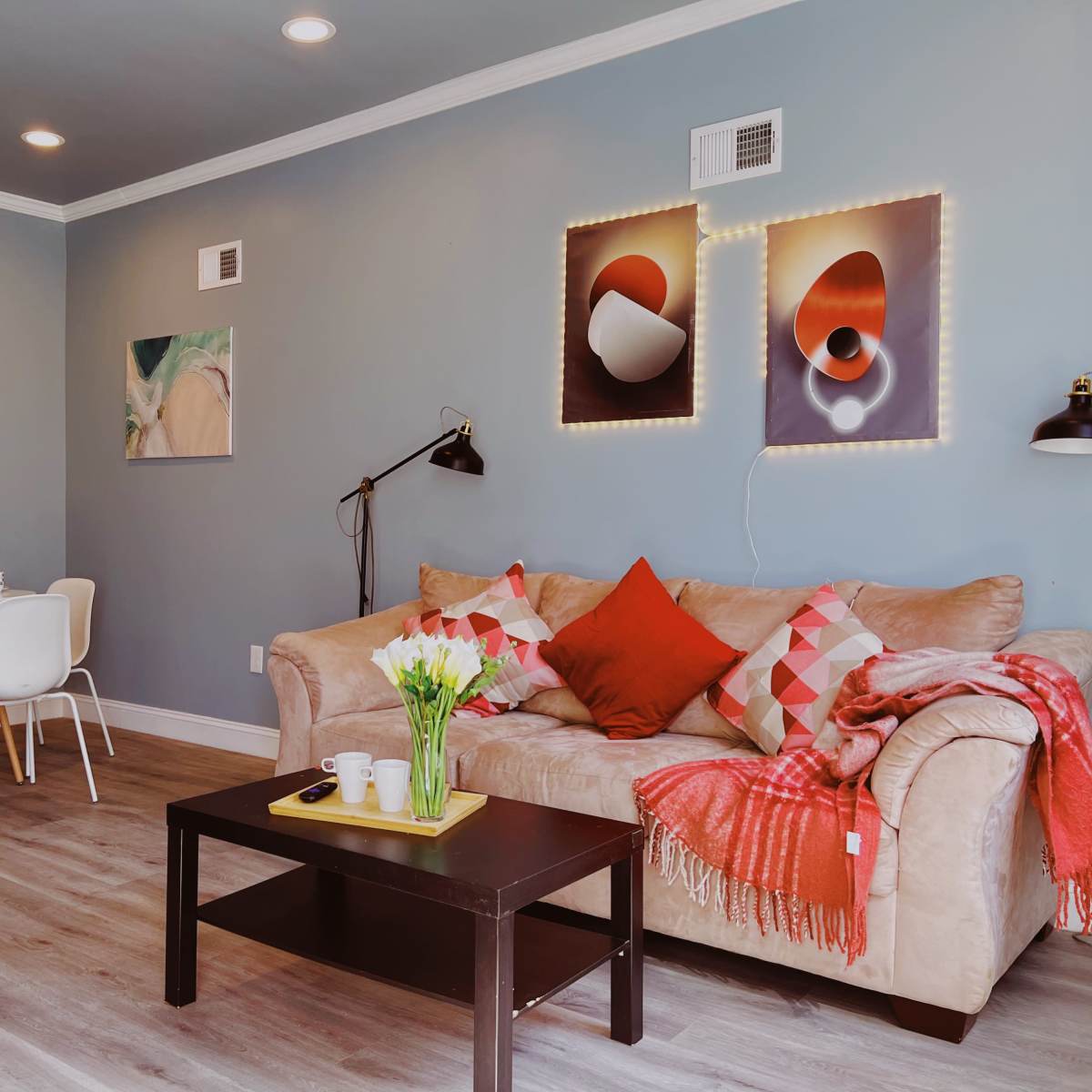 A modern living room with a couch, a coffee table, a dining area, and decorative wall art.