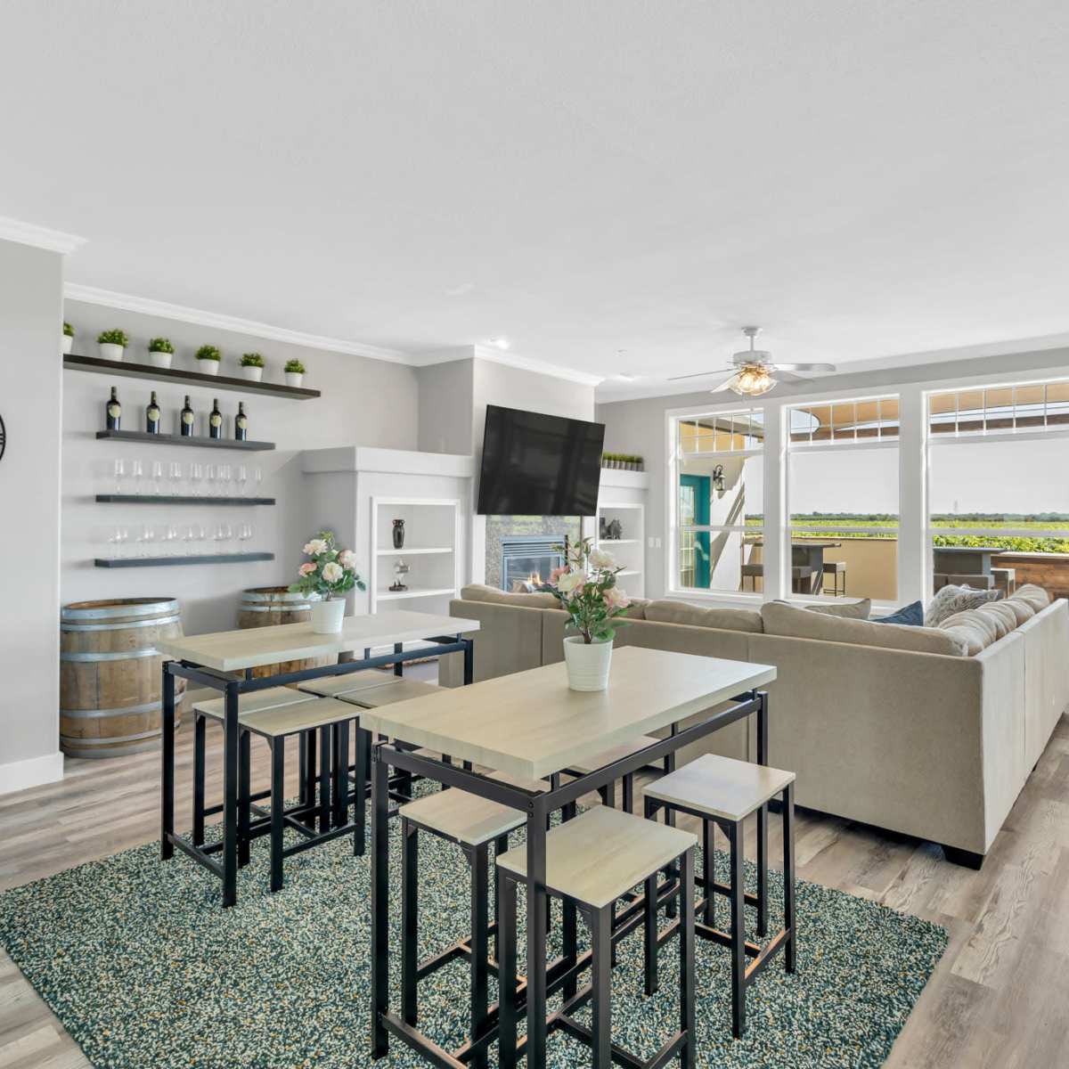 A modern living area with a seating arrangement, dining table, and large windows offering a view of the outdoors.