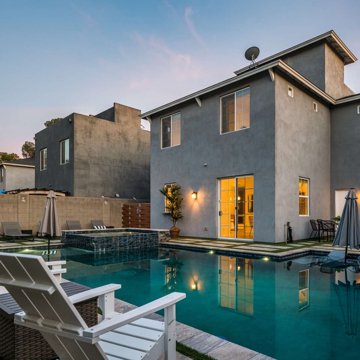 A modern two-story house with a pool and outdoor seating area in the backyard.