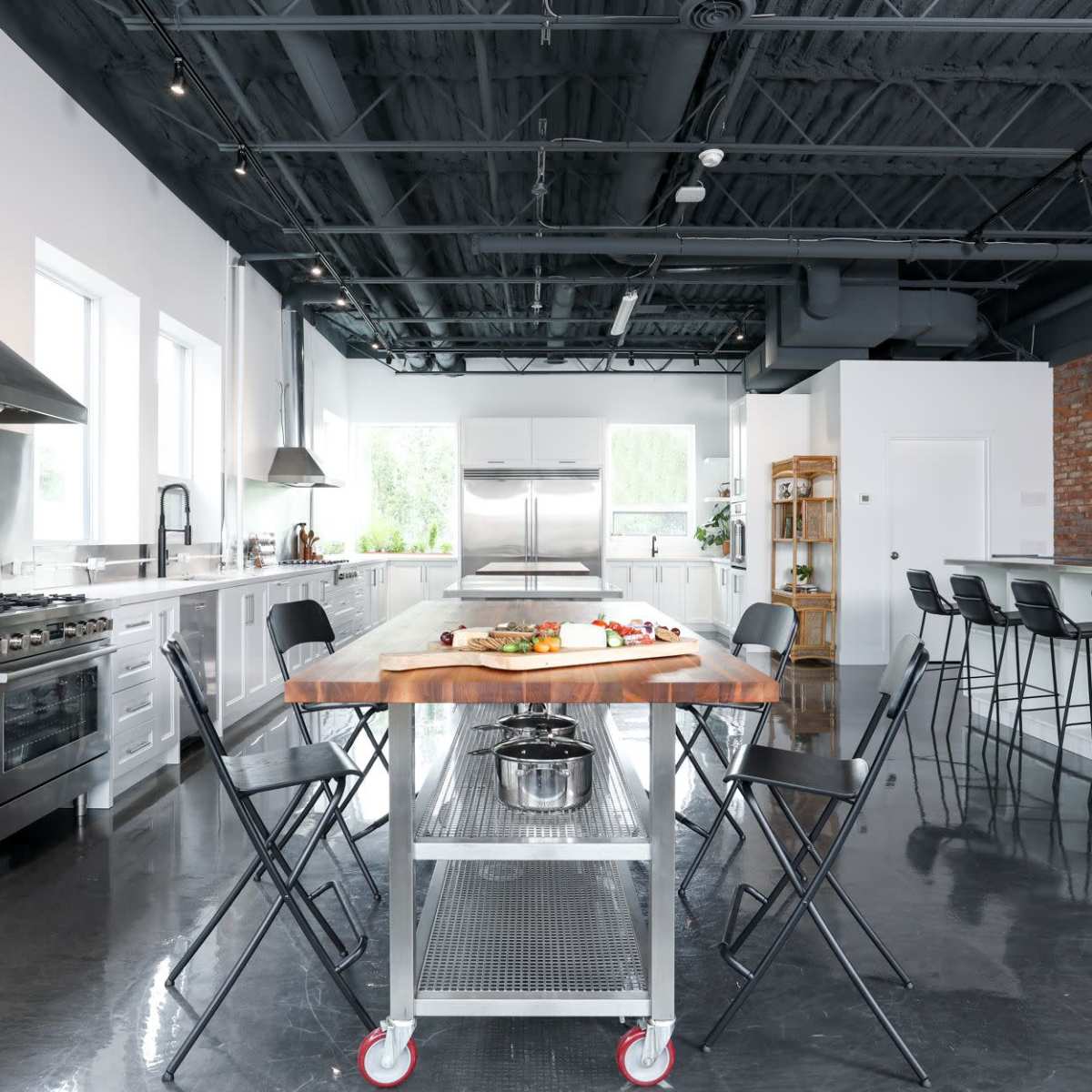 A modern kitchen features a central island with food preparations and sleek appliances along the walls.