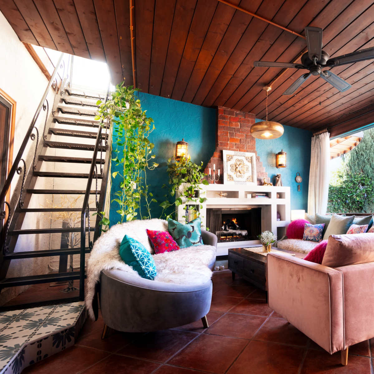 A cozy living room with a fireplace, plush seating, and large glass doors opening to a pool and garden area.