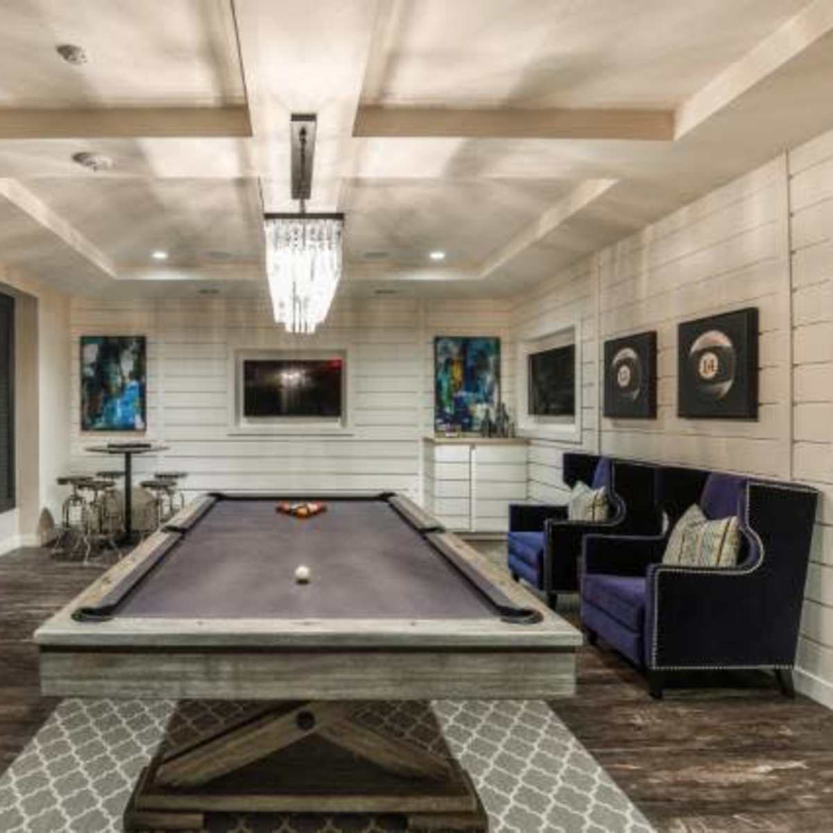 A recreational room with a billiard table, surrounded by plush seating and modern decor.