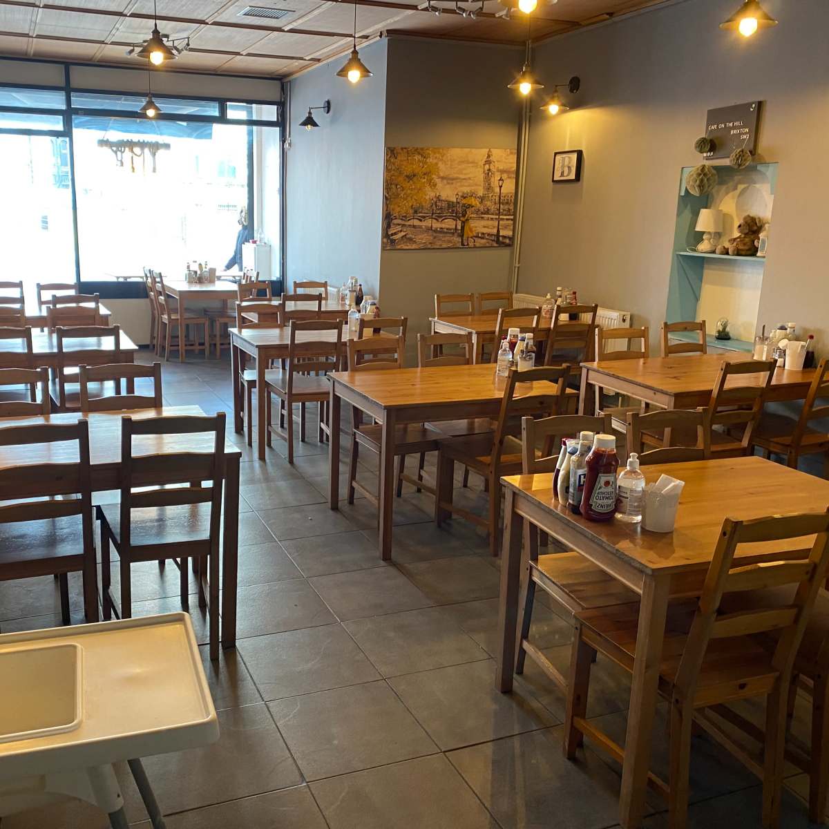 A spacious restaurant interior featuring wooden tables and chairs arranged neatly, with a few condiments on each table.