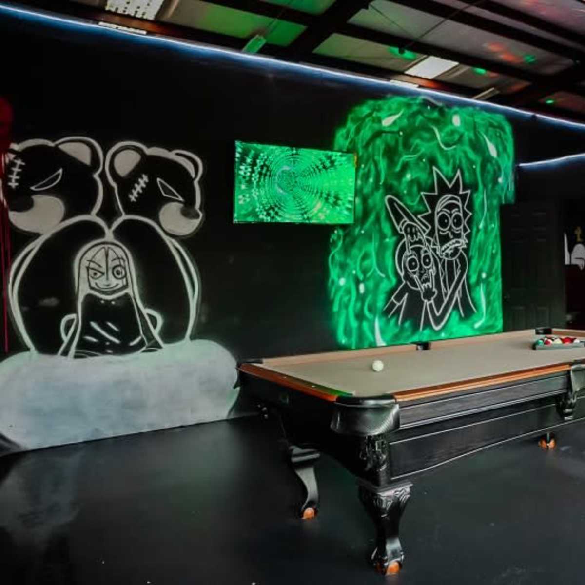A pool table in a room decorated with colorful graffiti and neon lighting.
