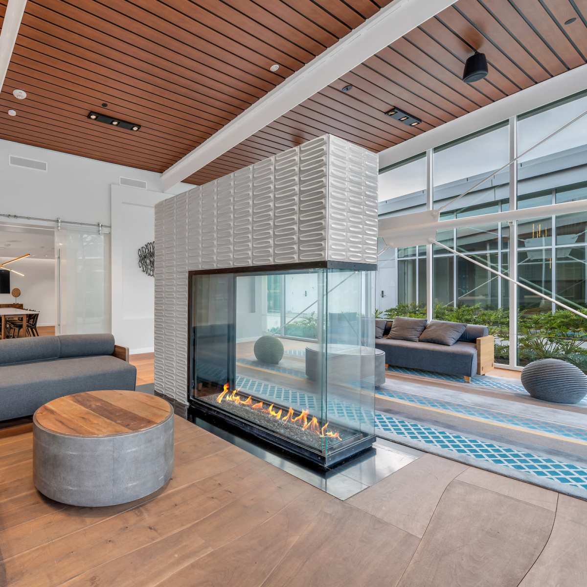 A modern lounge area featuring a sleek fireplace, contemporary furniture, and large windows that provide natural light.