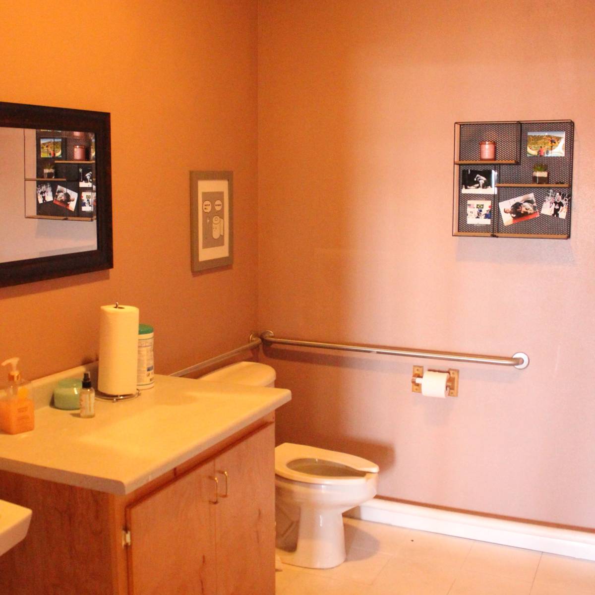 A bathroom featuring a beige wall, a toilet, a sink with a cabinet, and framed photos mounted on the wall.
