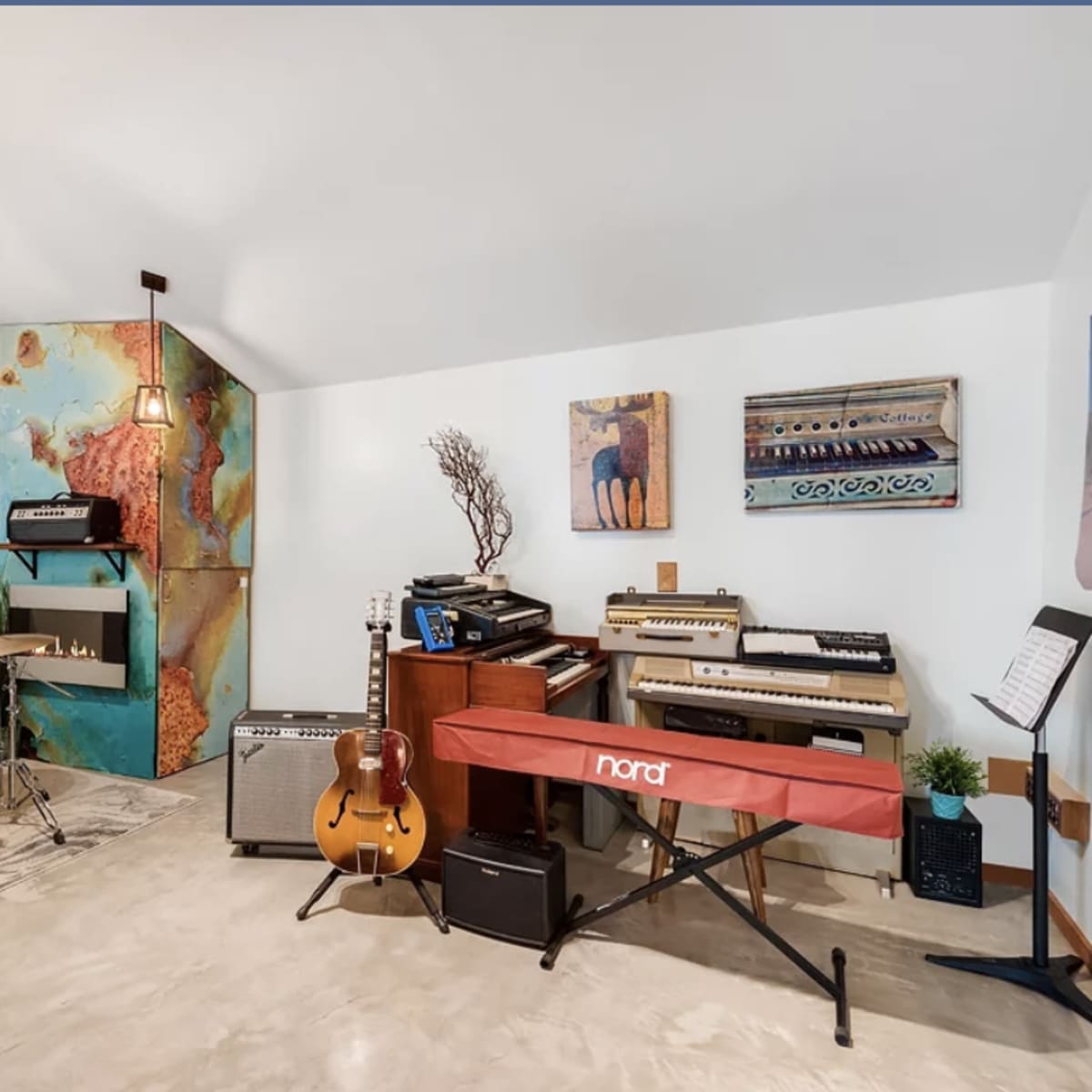 A music studio with a drum set, various musical instruments, and colorful wall art.