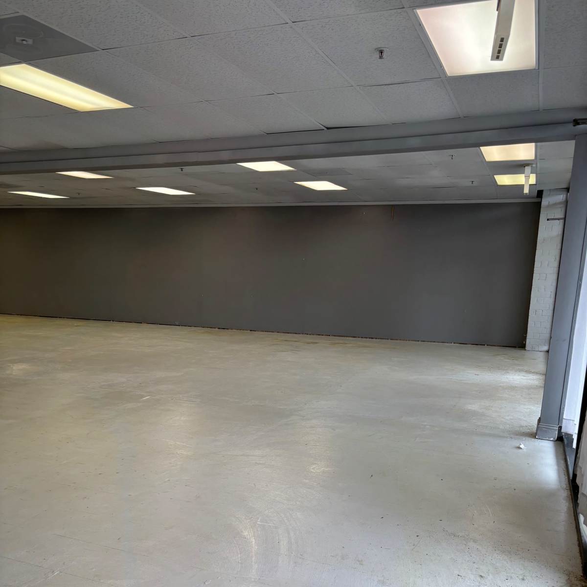 An empty commercial space with a concrete floor and gray walls.