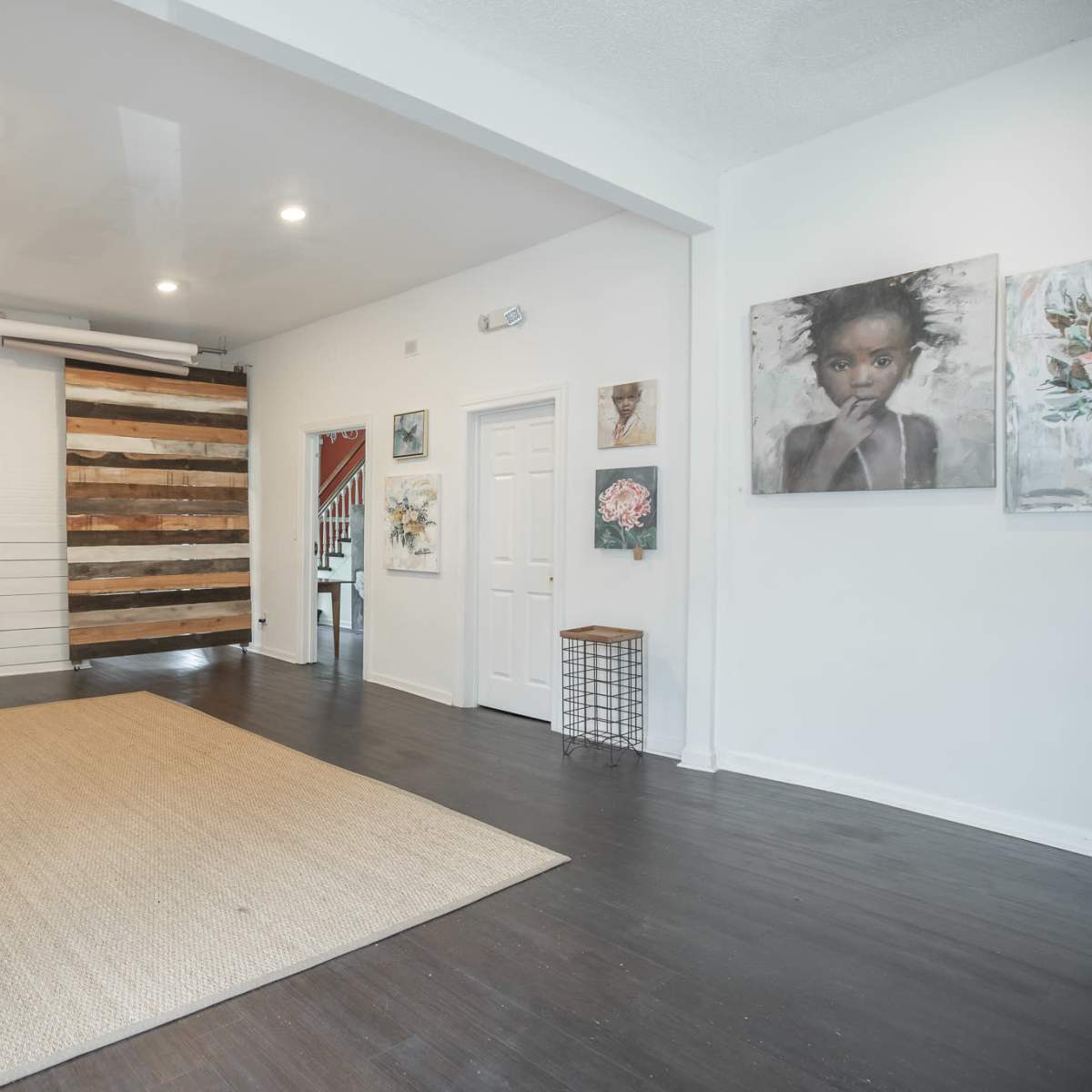 The room features a wooden floor, white walls, and a wall with a rustic wooden panel design, illuminated by overhead lights.