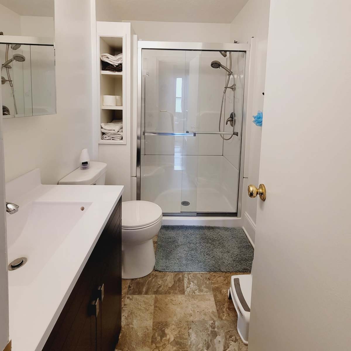 A clean bathroom with a glass shower enclosure, a toilet, and a vanity sink with a mirror above it.