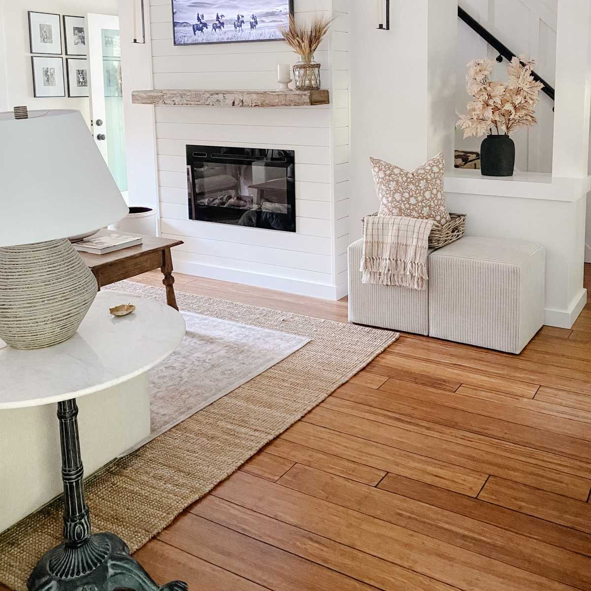 A cozy living room features a mounted TV above a wooden mantel, a light-colored coffee table, and a sofa with decorative pillows.