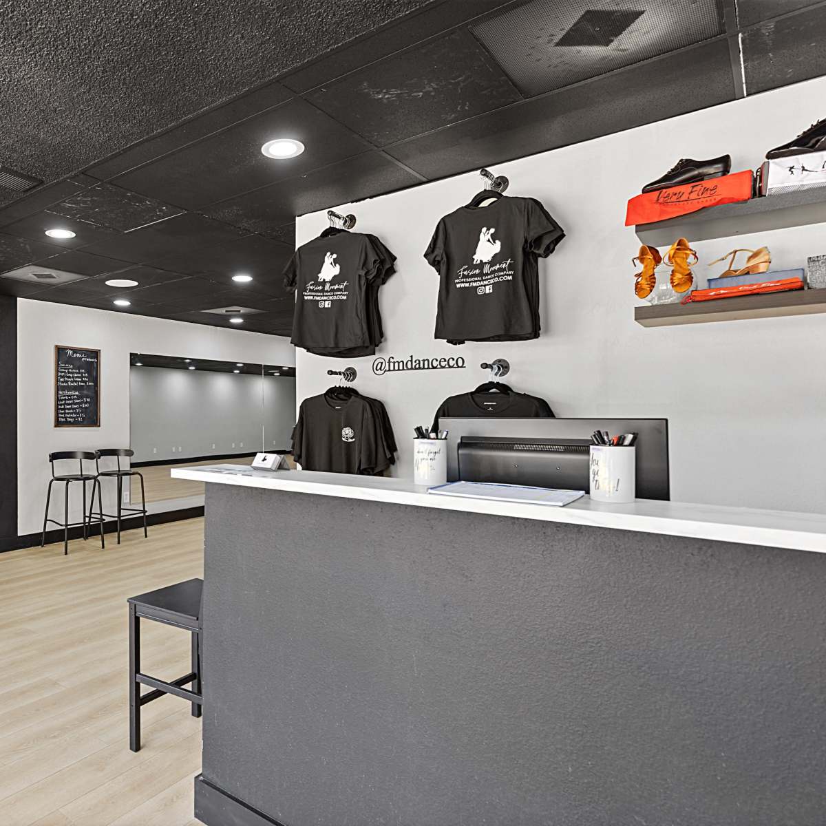 A boutique interior with a red dress on display, black clothing on hangers, and a reception counter.